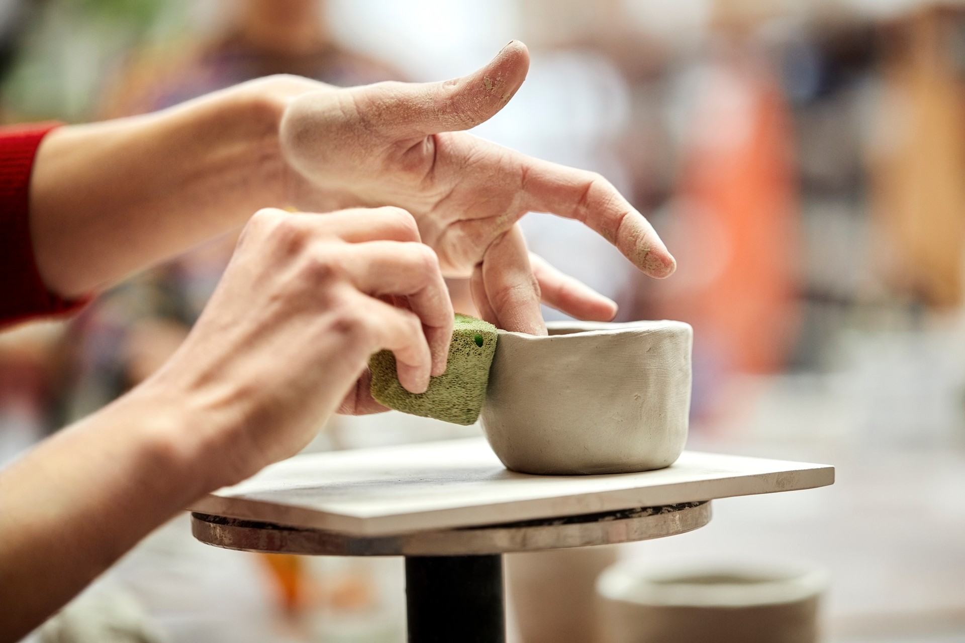 Woman's hands molding clay with sponge